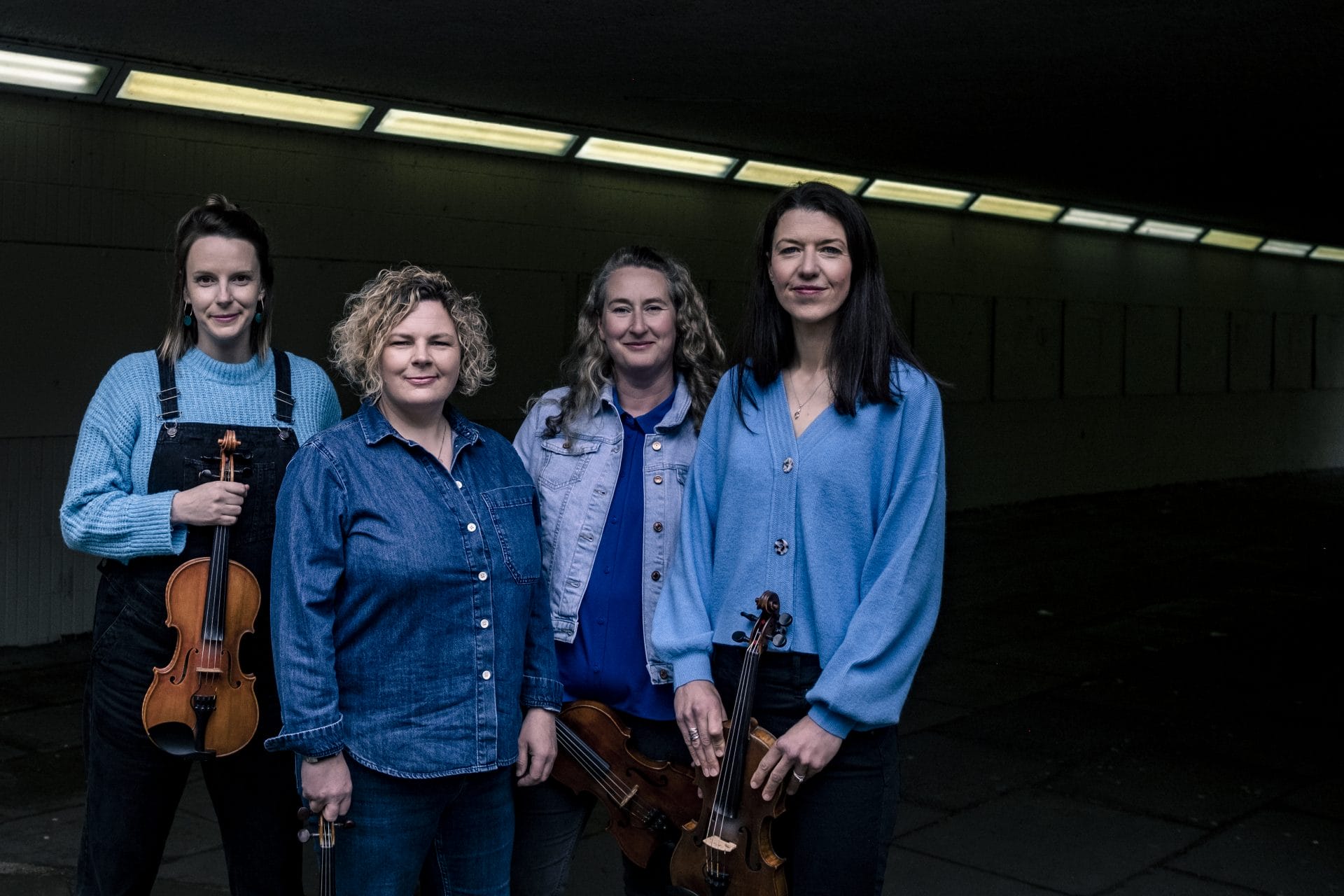 Innovative female musicians with violins performing at Moray Events in a modern, indoor setting.